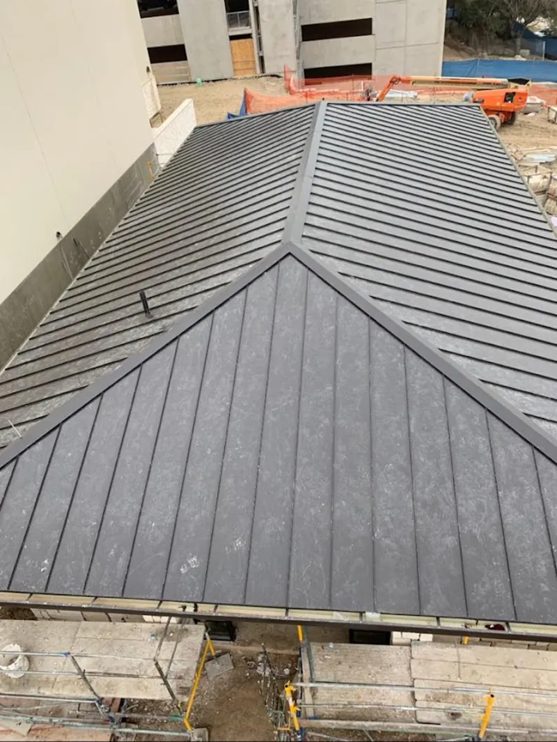 Commercial metal roof construction with crane equipment in Heeia